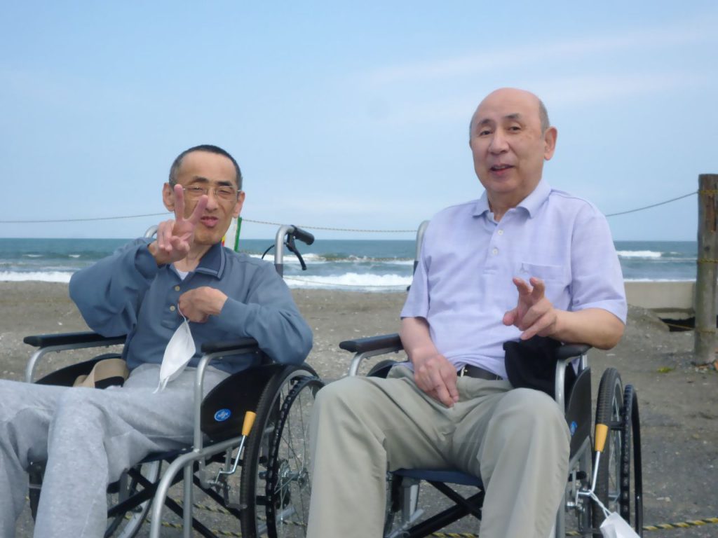 海岸での車椅子利用者による交流。入居者の野外活動風景。