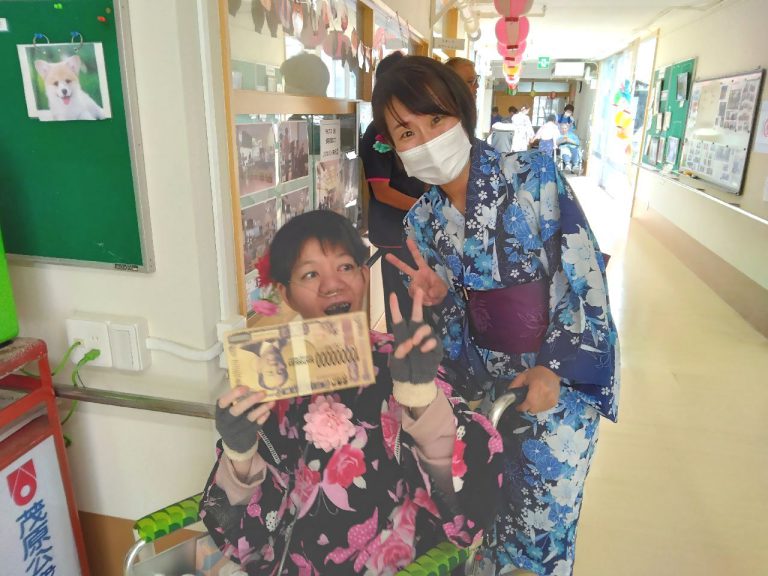 スタッフと入居者が廊下で作品を持って笑顔で交流している様子